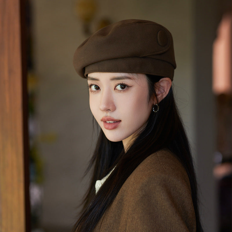 Woman wearing a brown beret and coat indoors
