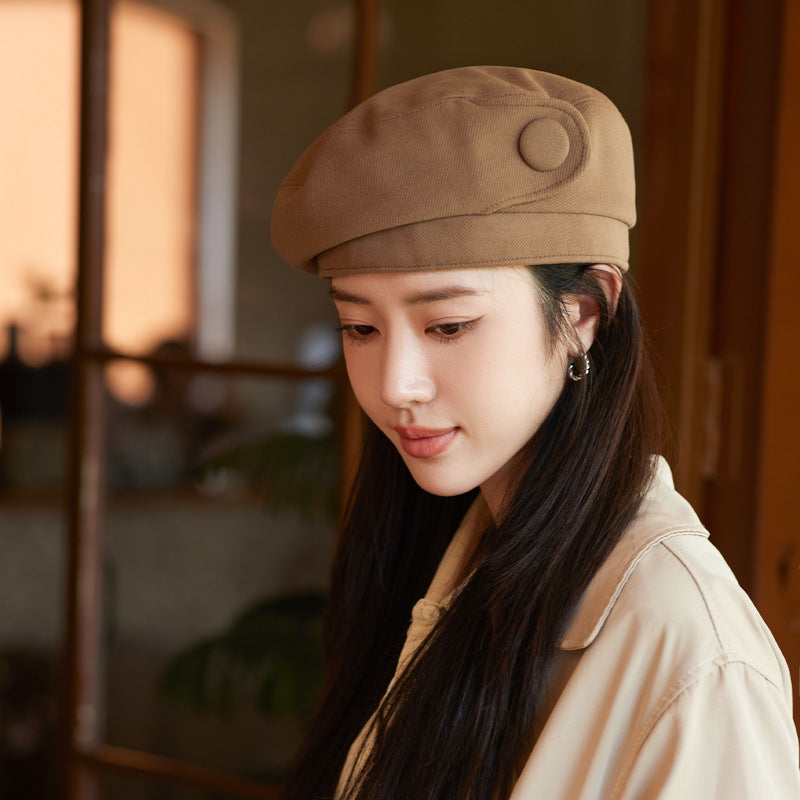 Woman wearing a brown cap indoors with a blurred background