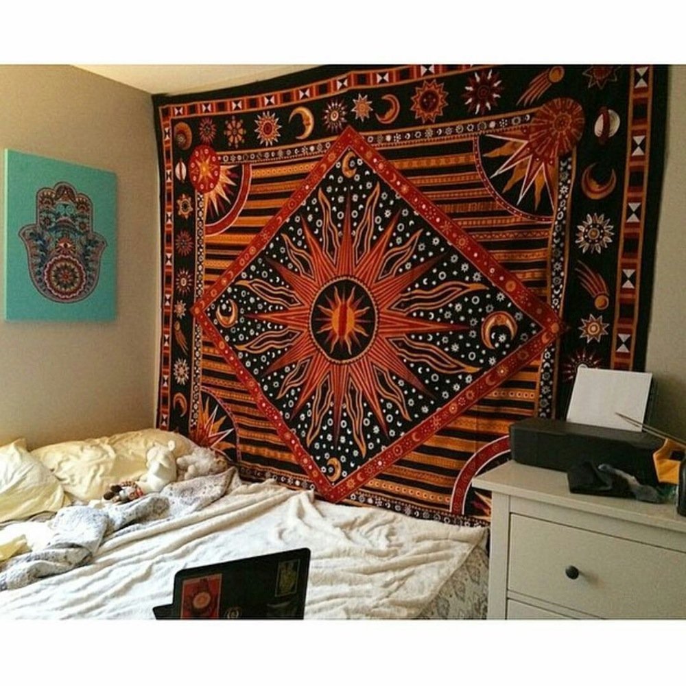 Decorative tapestry with celestial design hanging on a wall above a bed.
