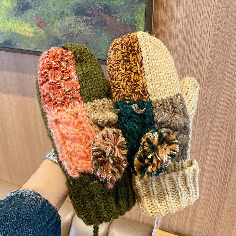 Colorful knitted mittens with pom-poms on a wooden surface.