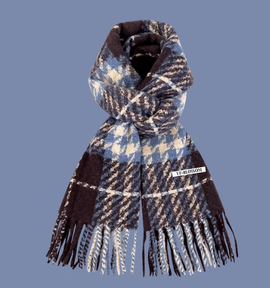 Plaid scarf with fringes and a visible brand label on a blue background