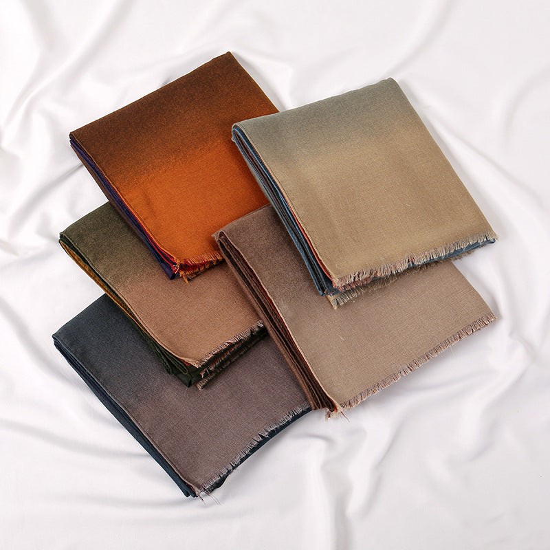 Stack of folded scarves in brown and beige tones on a white fabric background