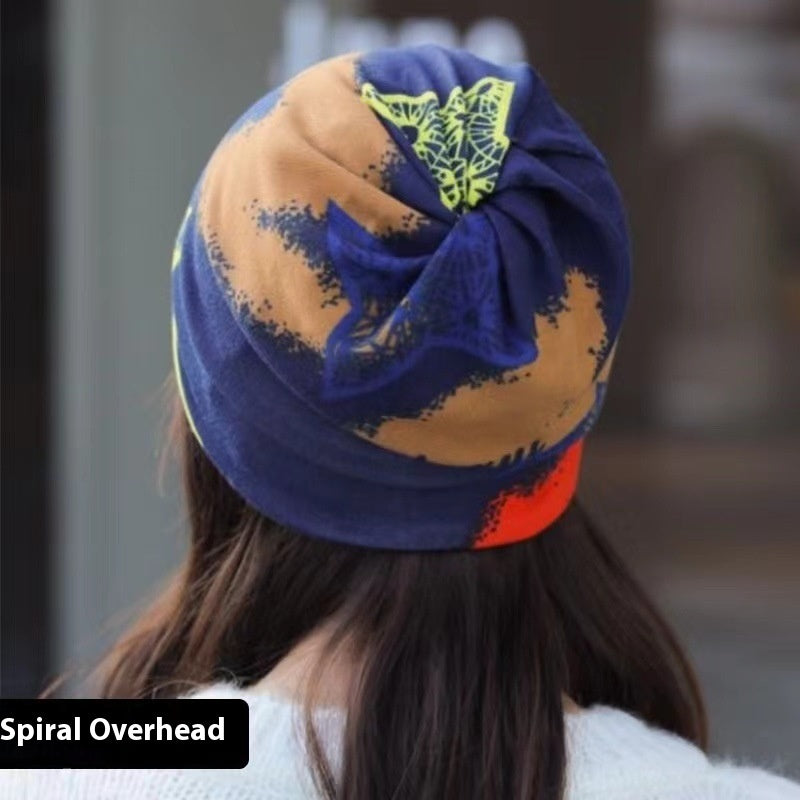 Colorful turban with a spiral pattern worn by a person, with a blurred background.