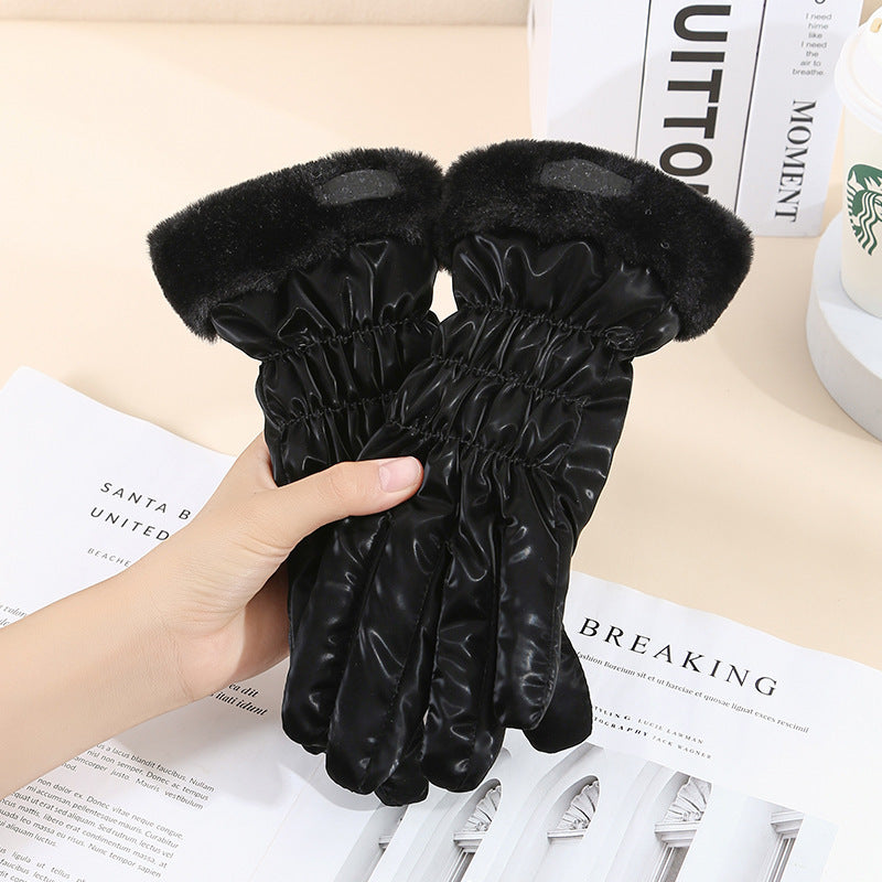 Black textured gloves held by a hand on a surface with papers underneath