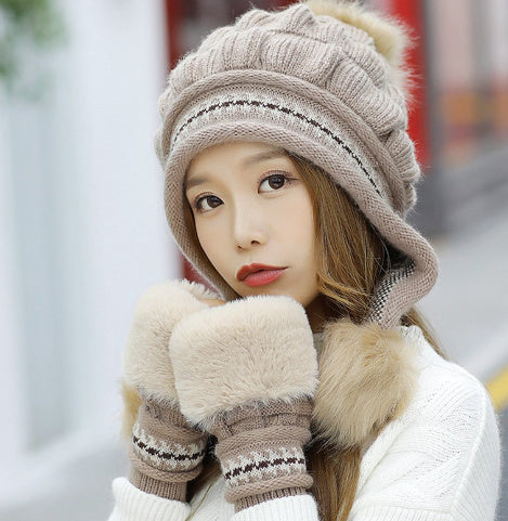 Woman wearing a beige knitted hat and scarf with fur trim in an outdoor setting