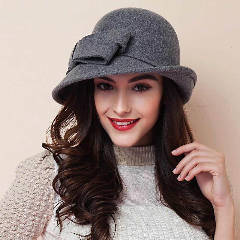 Woman wearing a gray hat with a bow on a beige background