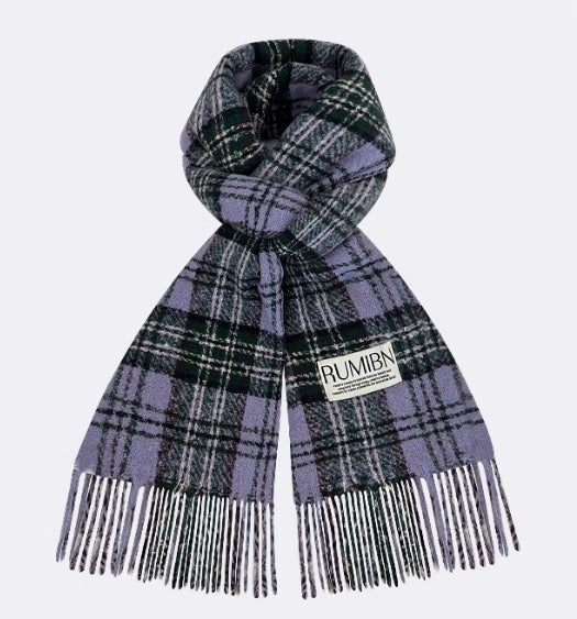 Plaid scarf with fringes and 'Rumbi' label on a light purple background