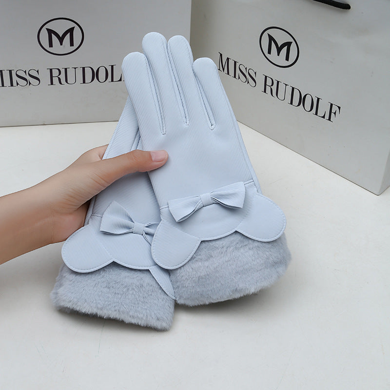 Light blue gloves with bow details held by a hand, against a Miss Rudolf branded background.