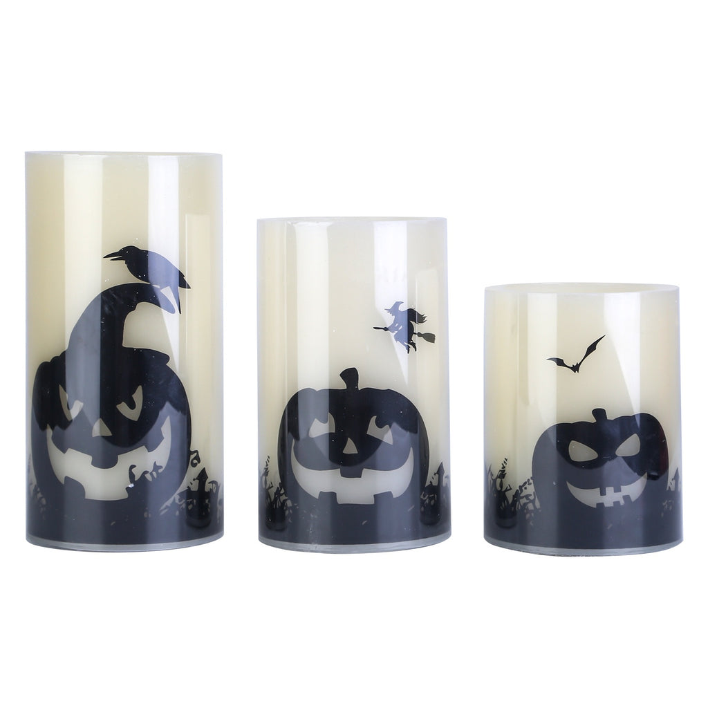 Set of three Halloween-themed candles with jack-o'-lantern designs on a white background