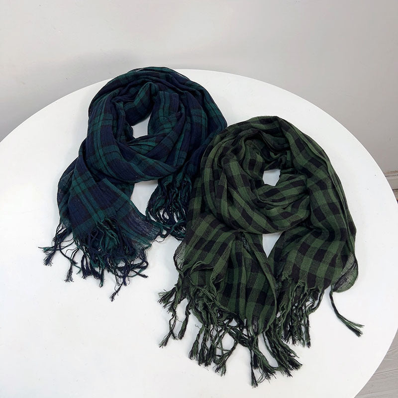 Two green plaid scarves on a white surface with a gray background