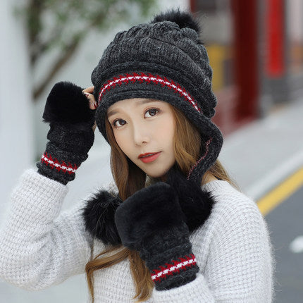 Woman wearing a gray knit hat, scarf, and gloves with red accents on a blurred street background.
