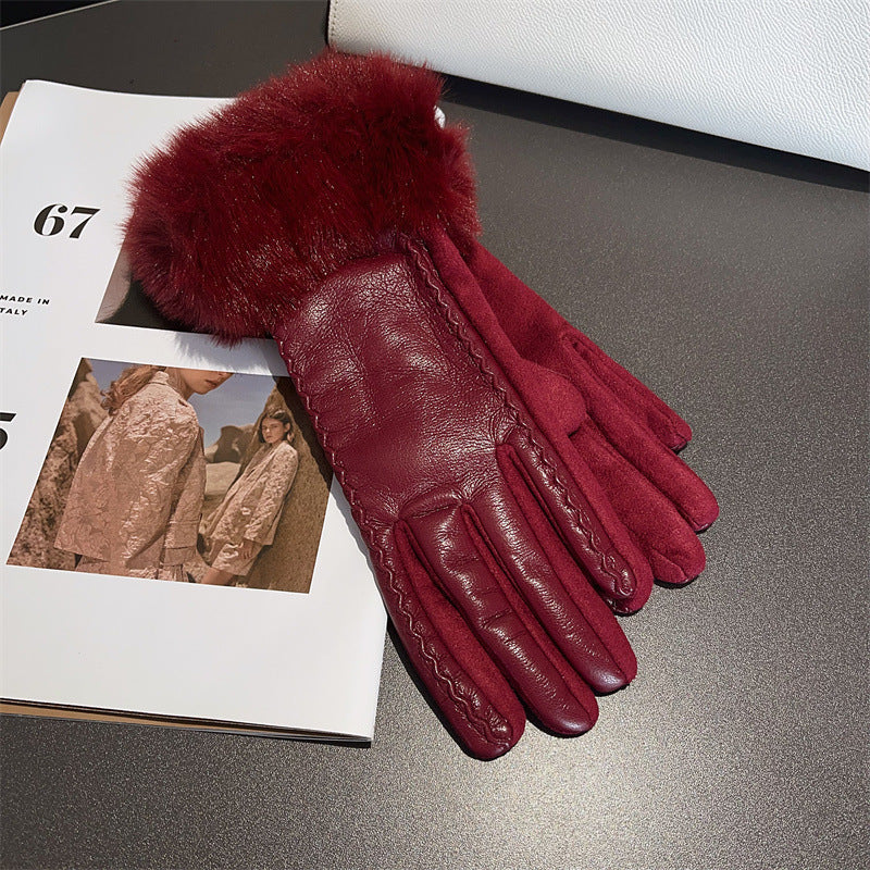 Red leather gloves with fur cuffs on a gray surface next to a magazine.