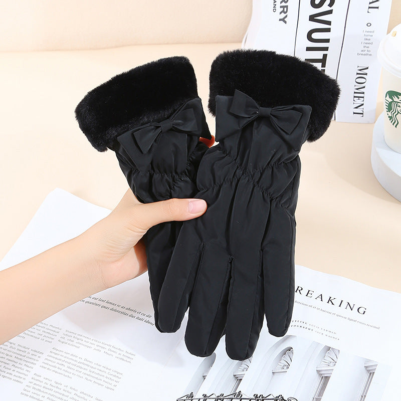 Black gloves with fur trim and a bow held by a hand on a newspaper background