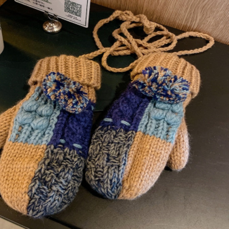 Pair of knitted mittens with blue and beige pattern on a dark surface