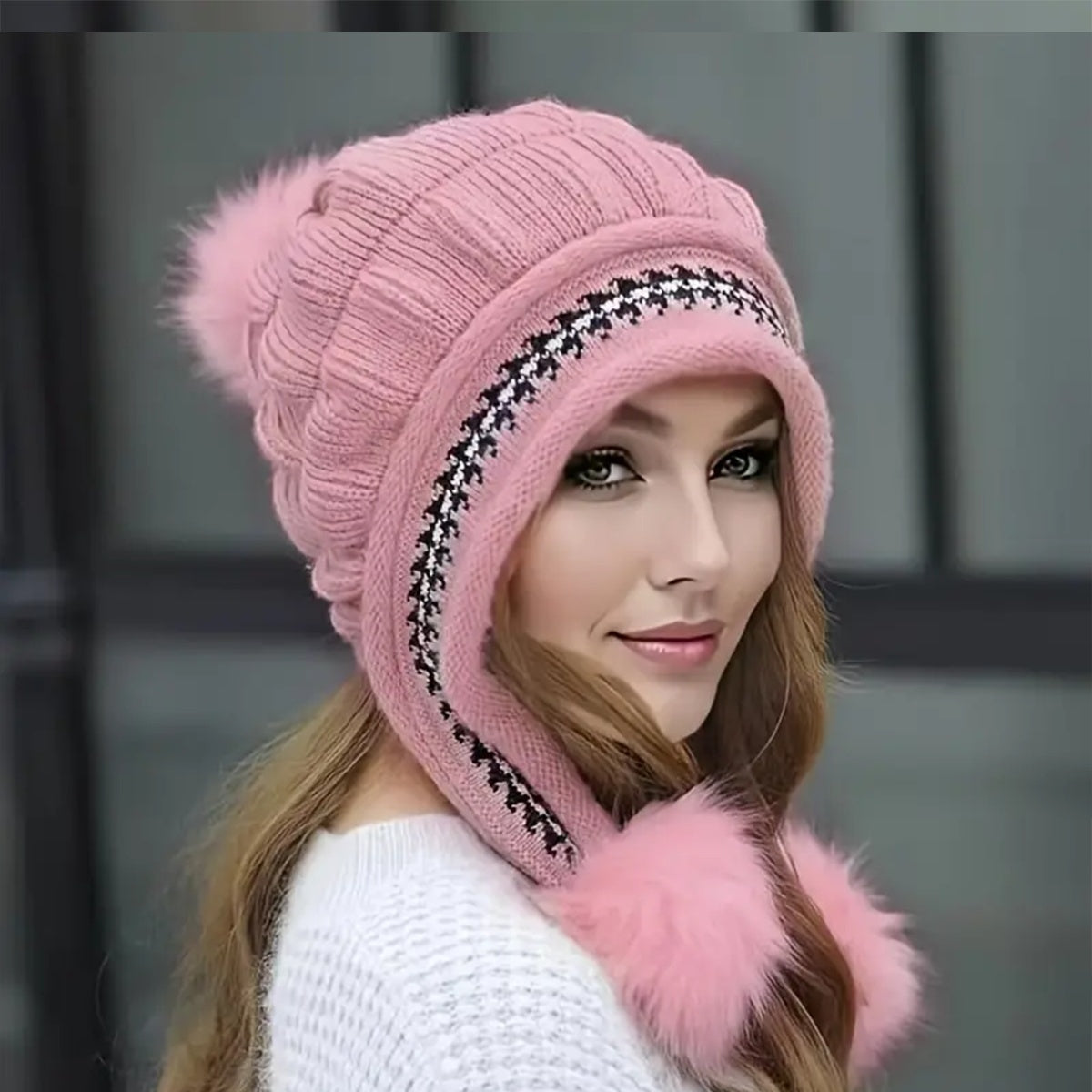 Woman wearing a pink knitted hat with fur trim against a blurred background
