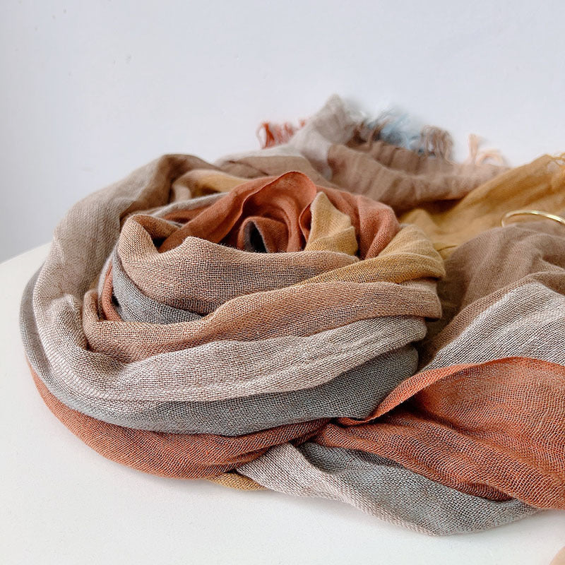 Stack of multicolored fabric scarves on a white surface