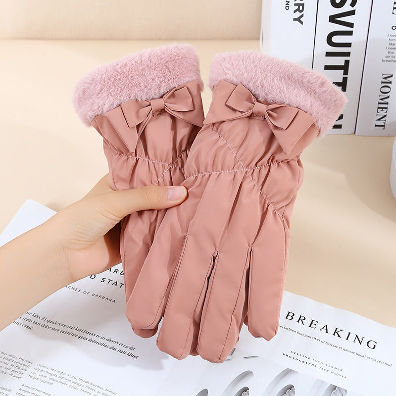 Pink gloves with bow details held by a hand on top of a magazine.