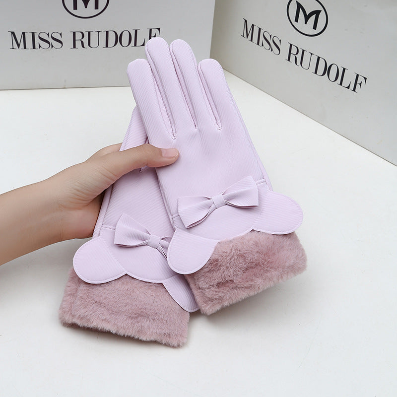Pink gloves with bow details held by a hand, brand 'MISS RUDOLF' visible in the background.