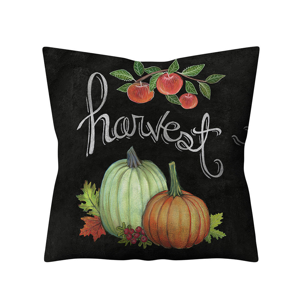 Decorative pillow with pumpkins, apples, and the word 'harvest' on a black background