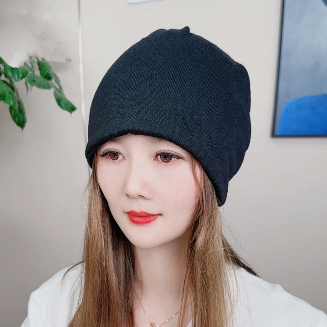 Person wearing a dark blue beanie indoors with a neutral background