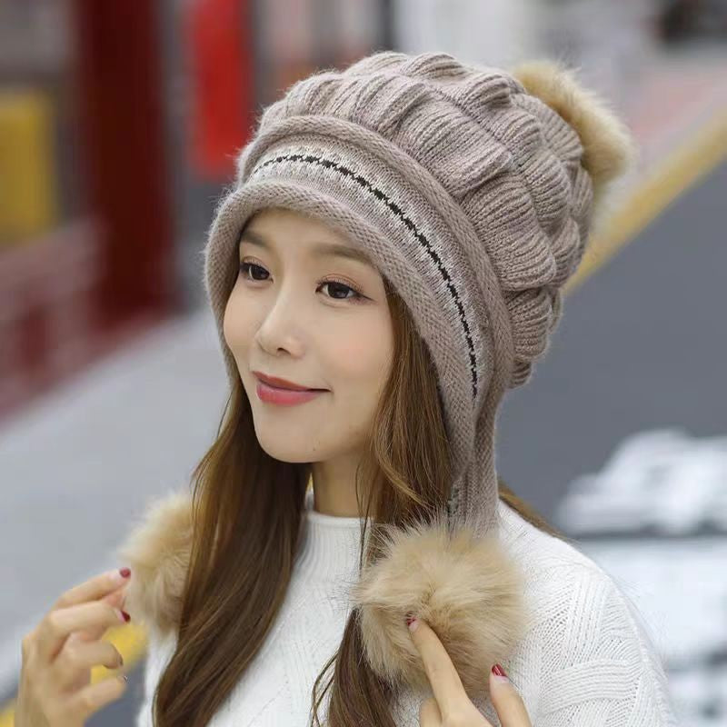 Woman wearing a beige knitted hat with pom-poms in an urban setting
