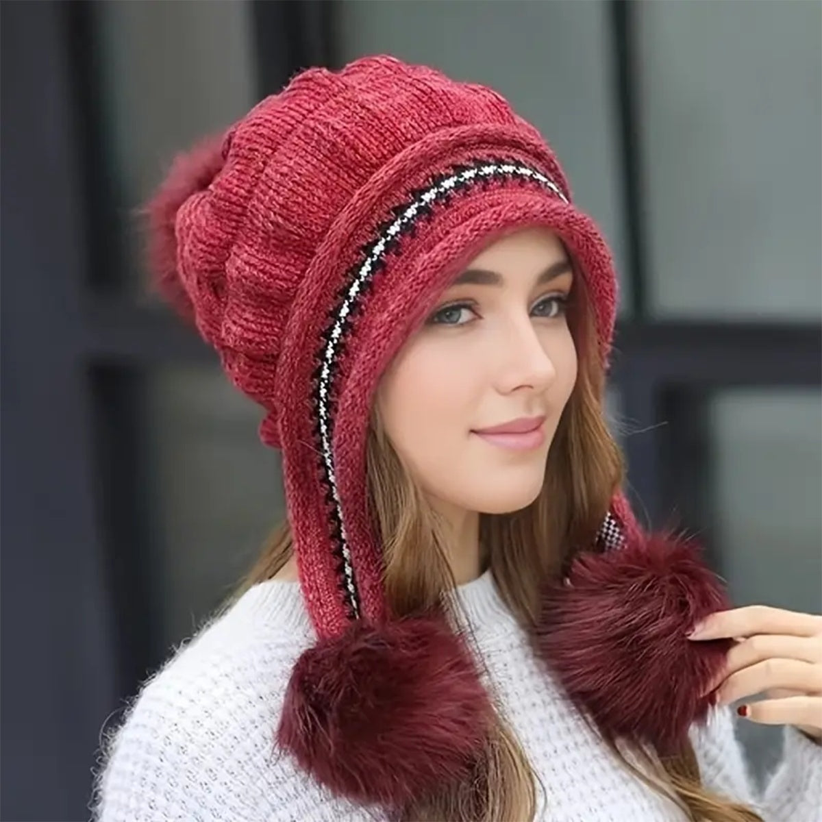 Woman wearing a red knitted hat with fur trim against a blurred background