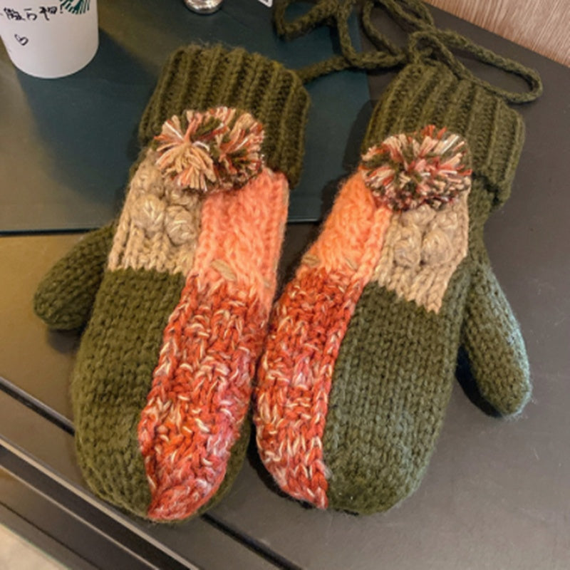 Pair of knitted mittens with a gradient design on a dark surface.
