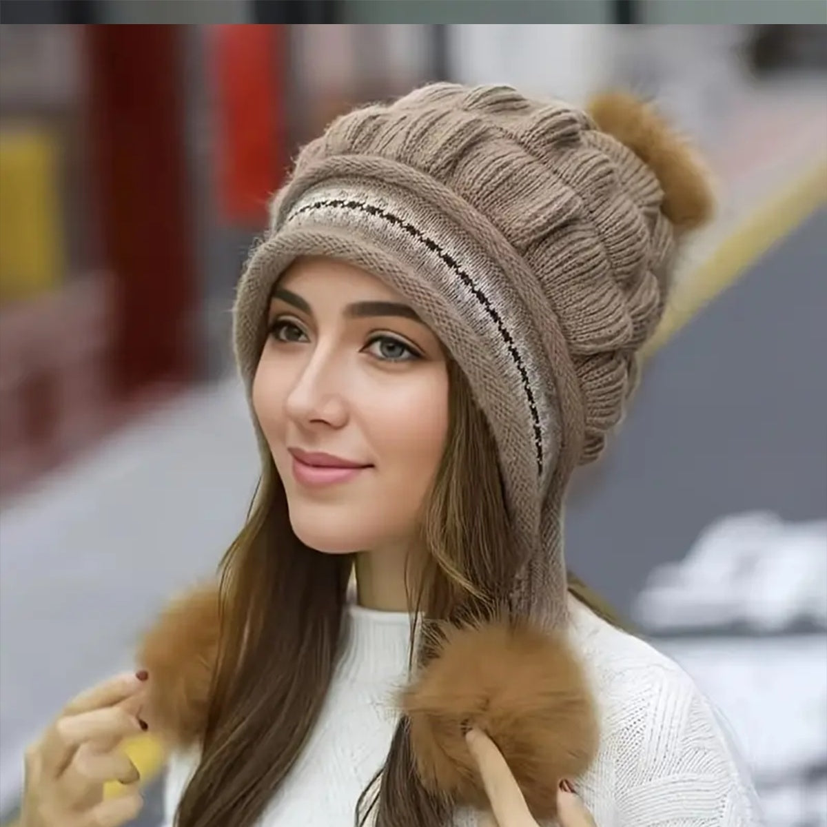 Woman wearing a brown knitted hat with pom-poms in an urban setting