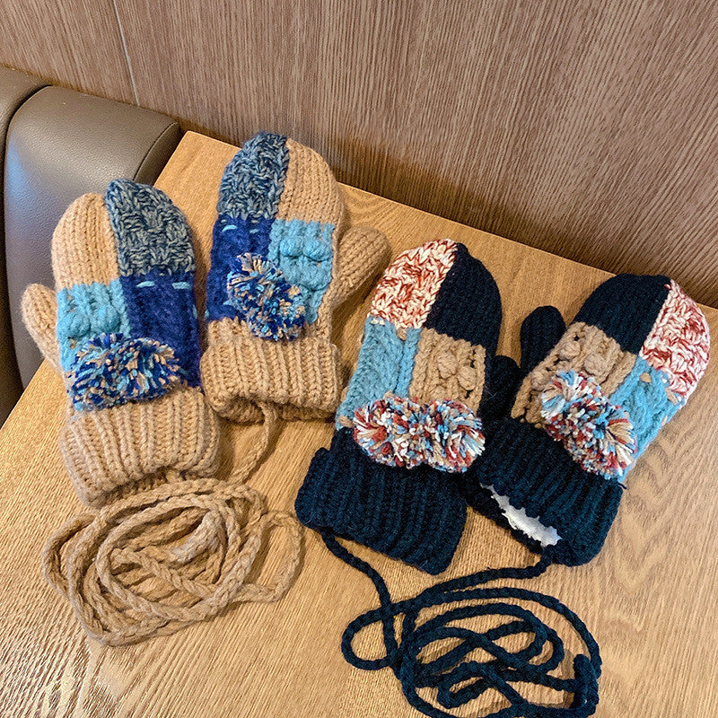 Pair of knitted mittens with blue and beige pattern on a wooden surface.