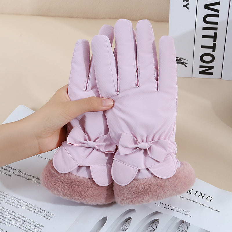 Pink gloves with bow details held by a hand on a magazine background