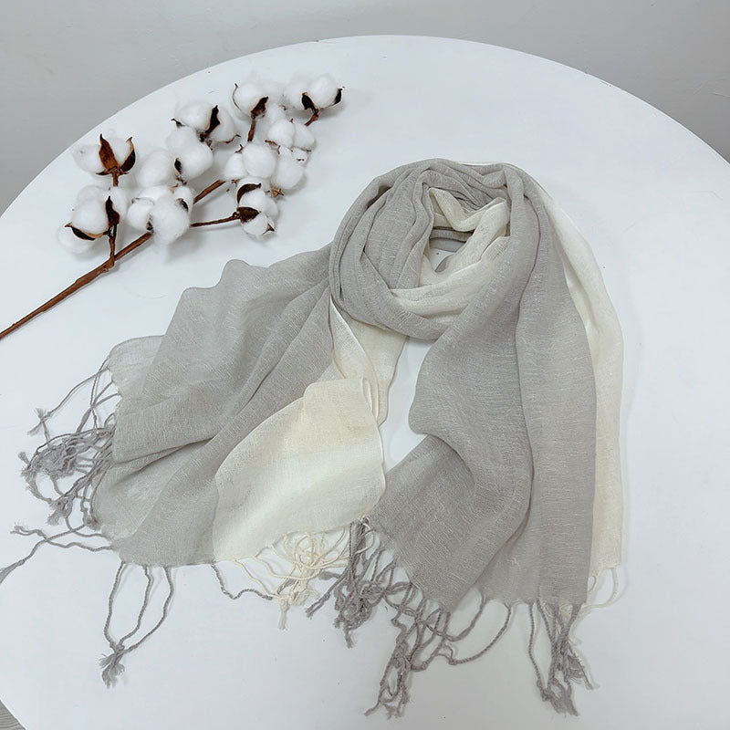 Gray and white scarf with cotton branches on a white surface