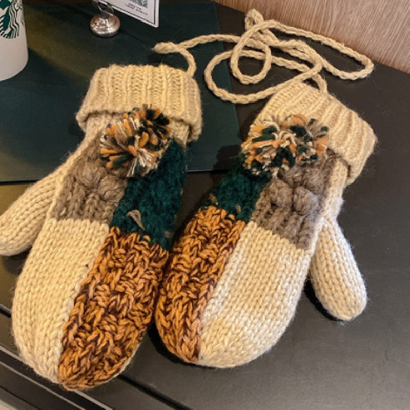 Pair of knitted mittens with autumnal design on a dark surface
