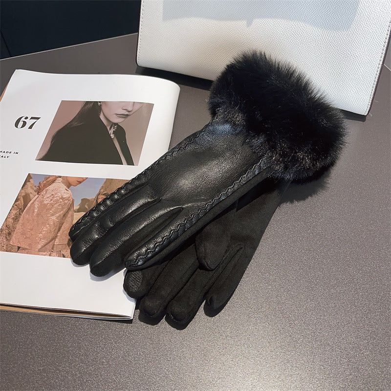 Black leather glove with fur cuff on a gray surface next to a magazine.
