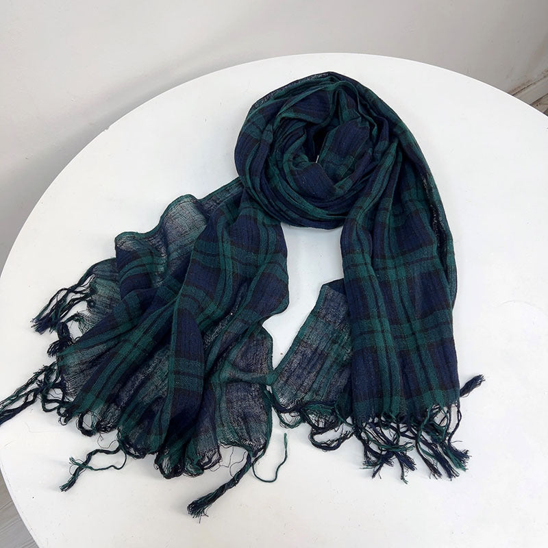 Plaid scarf with fringes on a white surface